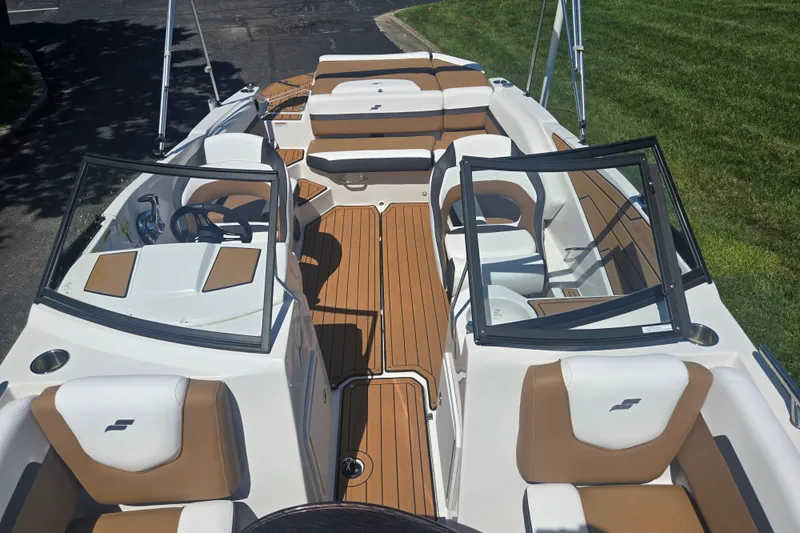 Slide: The Image of 2023 Starcraft SVX 230 IO boat interior with tan and white seating, open windshield, and wood-style flooring. - 21