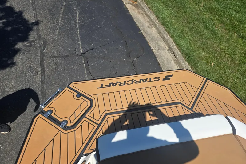 Slide: The Image of 2023 Starcraft SVX 230 IO boat deck with logo, parked on asphalt near grass. - 28