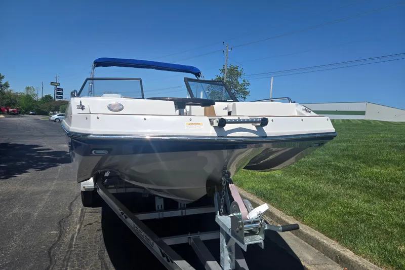 Slide: The Image of 2023 Starcraft SVX 230 IO boat on trailer, blue canopy, parked outdoors. - 6