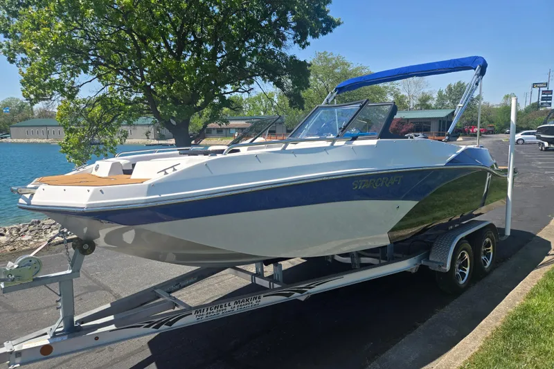 Slide: The Image of 2023 Starcraft SVX 230 IO boat on trailer by a lakeside, under a clear sky. - 8