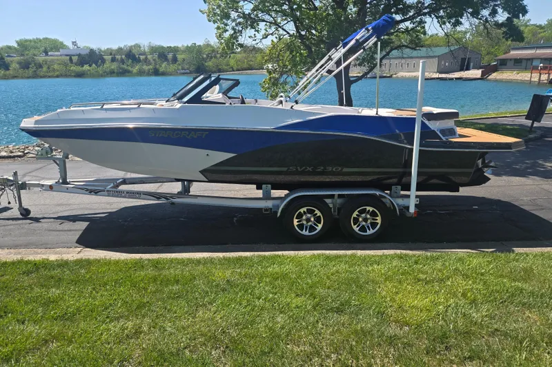 Slide: The Image of 2023 Starcraft SVX 230 IO boat on trailer by a scenic lake. - 9
