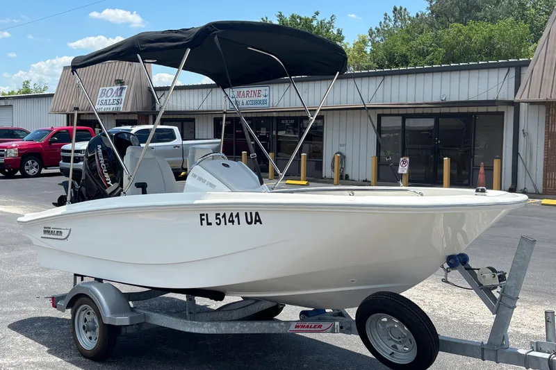 The Image of 2025 Boston Whaler 130 Super Sport boat on trailer, parked outside sales building. - 0