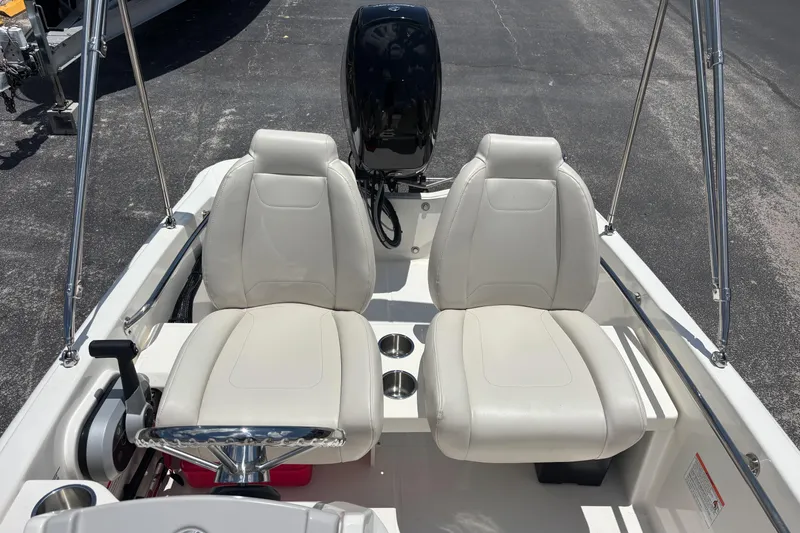 Slide: The Image of 2025 Boston Whaler 130 Super Sport boat interior with dual white seats and steering wheel. - 10