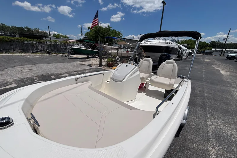 Slide: The Image of 2025 Boston Whaler 130 Super Sport boat with seating, docked under a clear blue sky. - 11