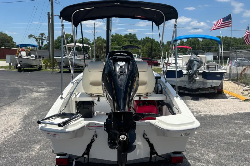 Slide: The Image of 2025 Boston Whaler 130 Super Sport boat with outboard motor, parked outdoors under a clear sky. - 13