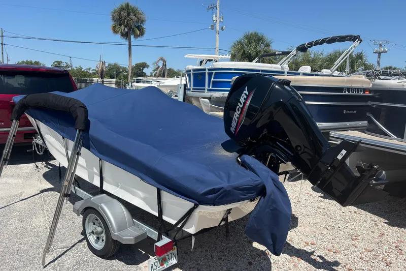 Slide: The Image of 2025 Boston Whaler 130 Super Sport boat with Mercury engine, covered and on a trailer. - 15