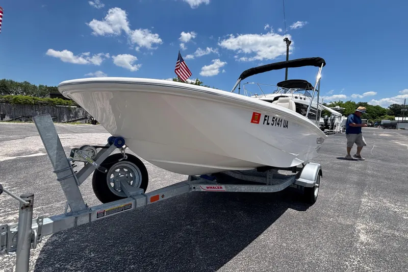 Slide: The Image of 2025 Boston Whaler 130 Super Sport boat on trailer under clear blue sky. - 17