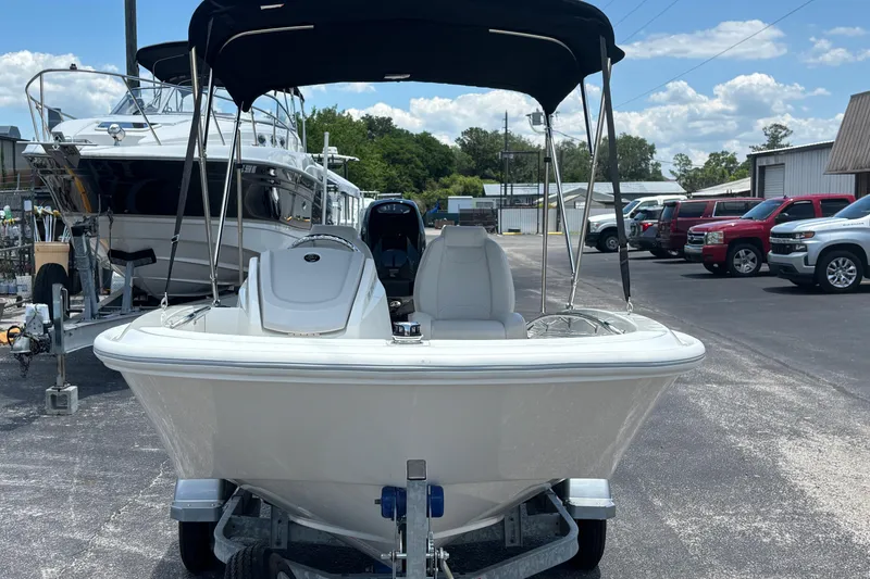 Slide: The Image of 2025 Boston Whaler 130 Super Sport boat on trailer, parked outdoors under a clear sky. - 2