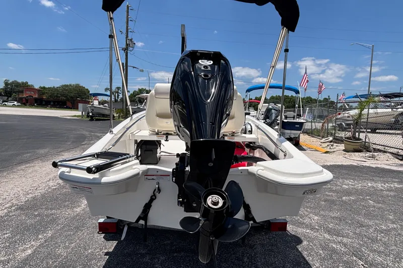 Slide: The Image of 2025 Boston Whaler 130 Super Sport boat, rear view with outboard motor, parked outdoors. - 34