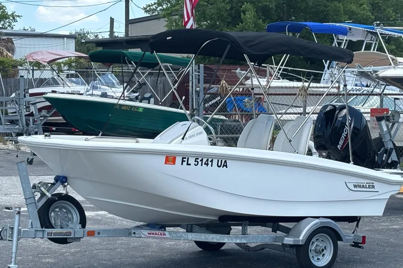Slide: The Image of 2025 Boston Whaler 130 Super Sport boat on trailer, parked outdoors. - 4