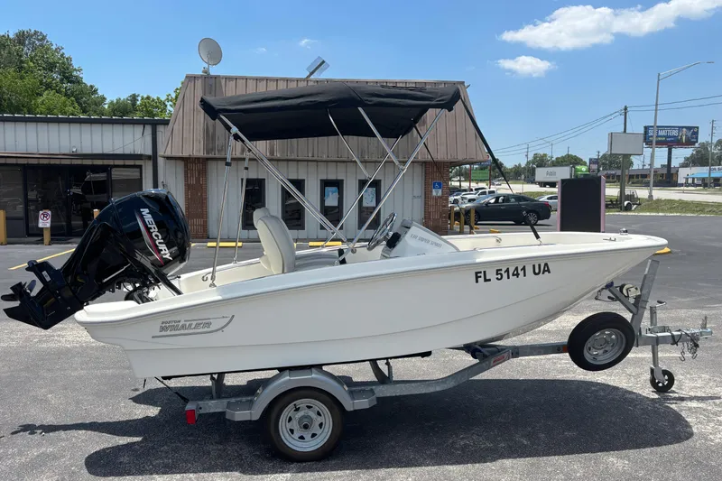 Slide: The Image of 2025 Boston Whaler 130 Super Sport boat on trailer, parked outdoors. - 6