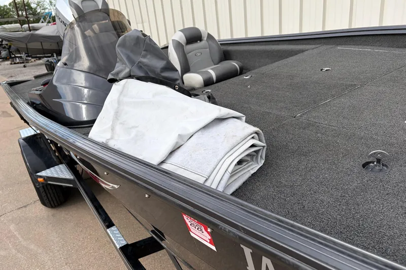 Slide: The Image of 2018 Polarcraft TX 195 boat with folded tarp on deck, parked outdoors. - 15