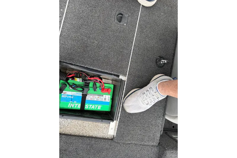 Slide: The Image of 2018 Polarcraft TX 195 boat interior with Interstate deep cycle battery and carpeted flooring. - 18