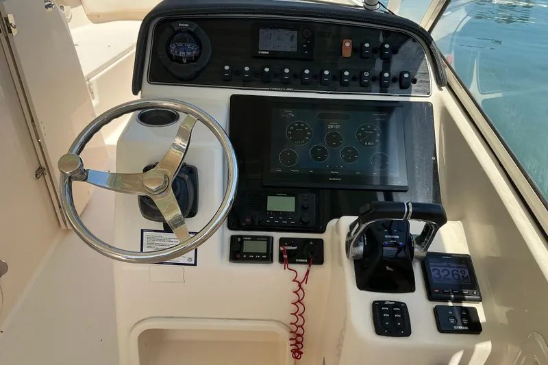 Slide: The Image of 2018 Grady-White Freedom 285 boat dashboard with steering wheel and navigation controls. - 20