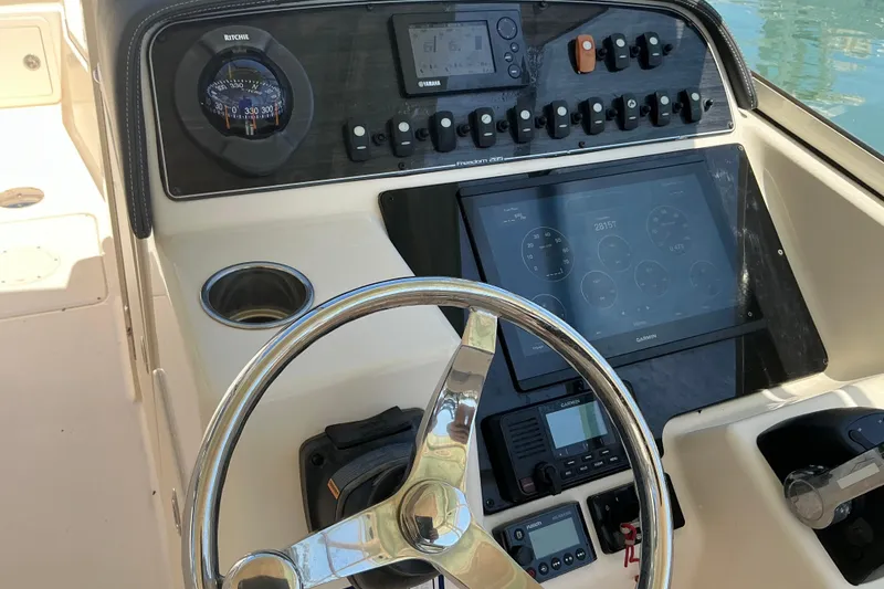 Slide: The Image of 2018 Grady-White Freedom 285 boat dashboard with steering wheel and navigation instruments. - 22