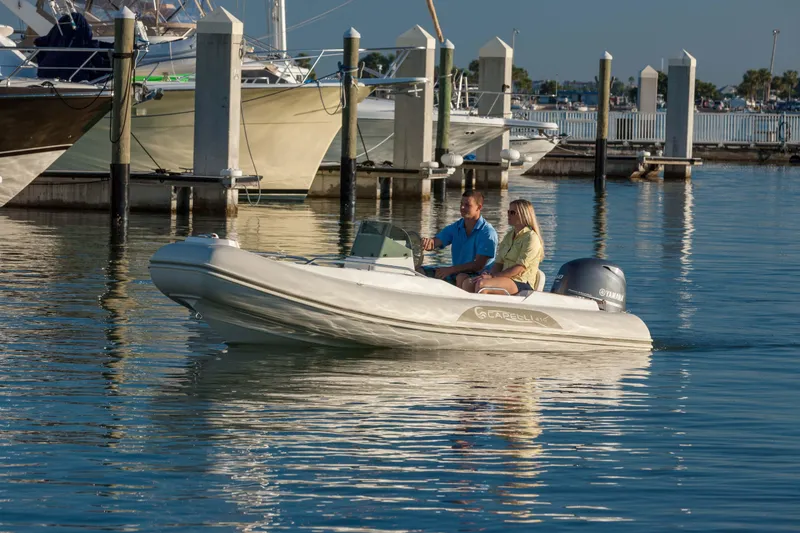 Slide: The Image of 2023 Capelli Tempest 410 Yacht Tender cruising in a marina with two passengers. - 2