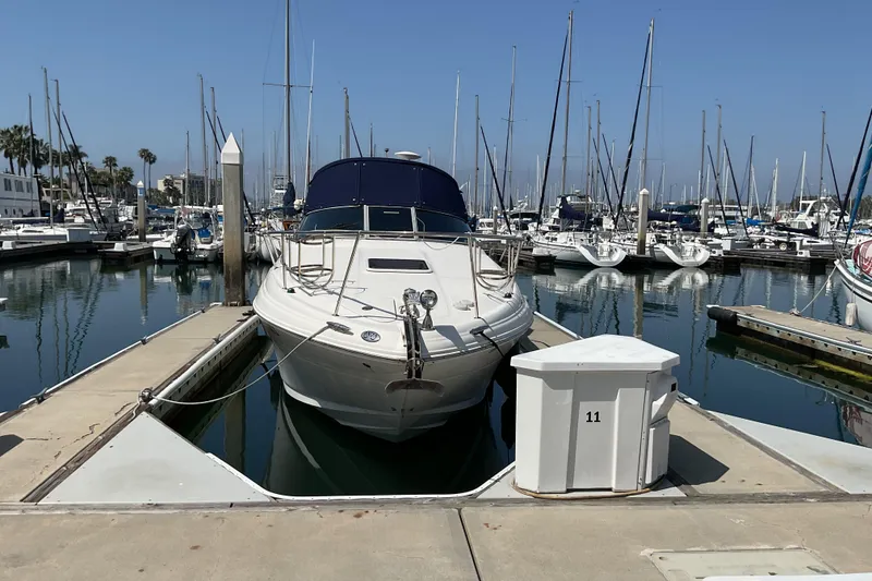 Slide: The Image of 2005 Sea Ray Sundancer 280 docked at a marina with sailboats in the background. - 2