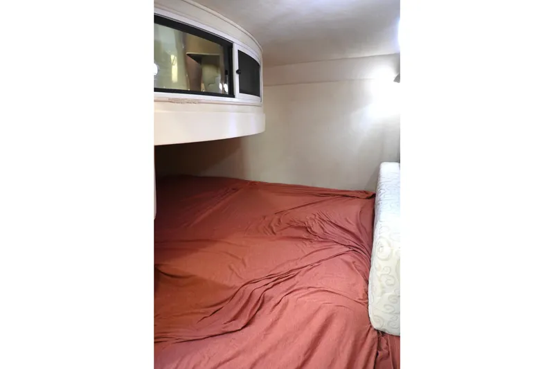 Slide: The Image of 2005 Sea Ray Sundancer 280 cabin interior with red bedding and overhead storage. - 28
