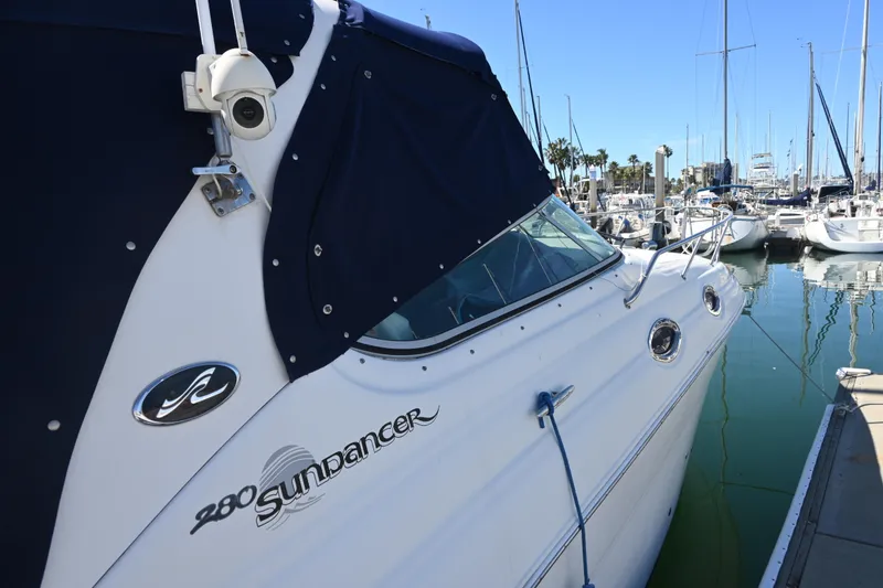 Slide: The Image of 2005 Sea Ray Sundancer 280 docked at marina, featuring sleek design and blue cover. - 6