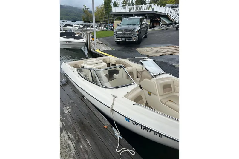 The Image of 2001 Stingray 200 LS/LX boat docked by a lakeside with a truck nearby. - 0