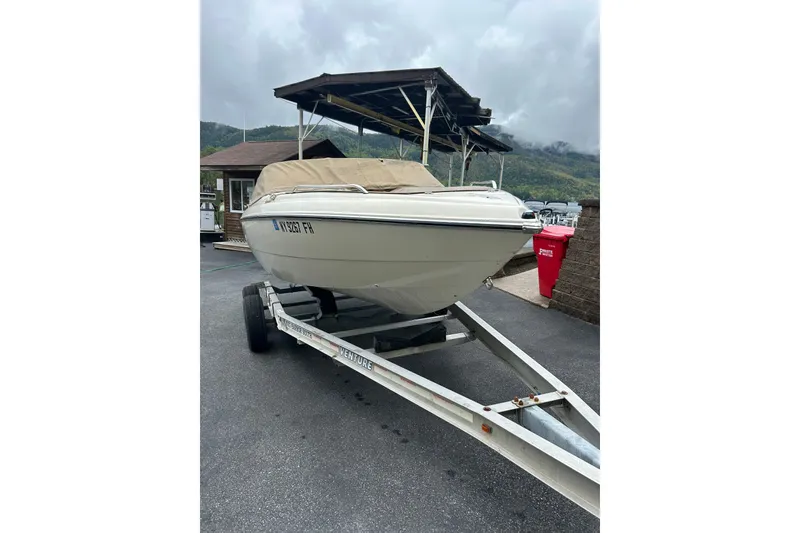 Slide: The Image of 2001 Stingray 200 LS/LX boat on trailer, covered, parked near marina with cloudy sky. - 2