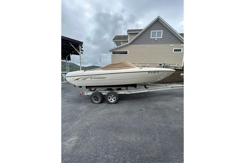 Slide: The Image of 2001 Stingray 200 LS/LX boat on trailer, parked near a house under cloudy skies. - 3