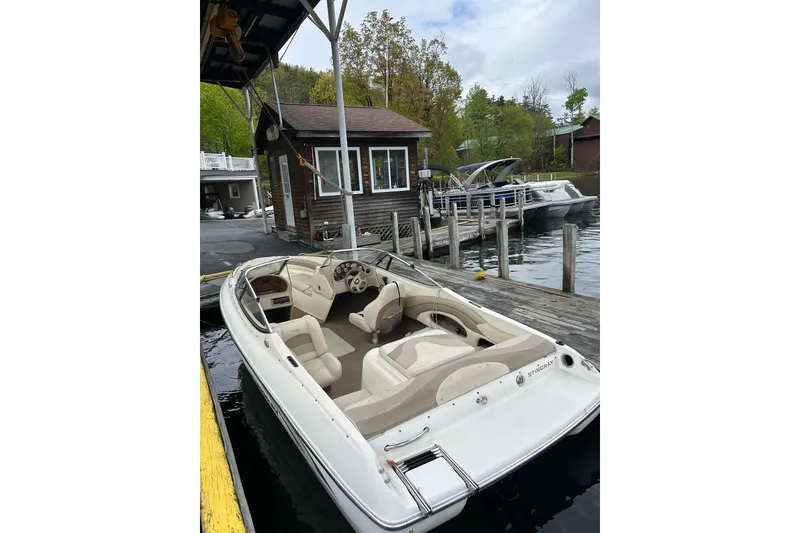 Slide: The Image of 2001 Stingray 200 LS/LX boat docked at a lakeside marina with scenic background. - 6