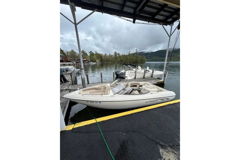 Slide: The Image of 2001 Stingray 200 LS/LX boat docked by a scenic lake under cloudy skies. - 8