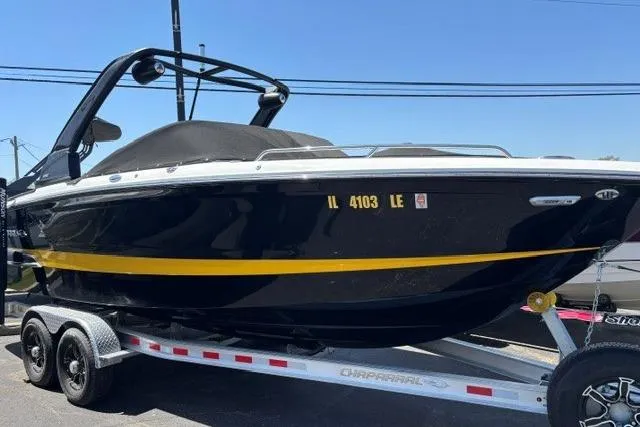 The Image of 2023 Chaparral 267 SSX boat on trailer, black with yellow stripe, parked outdoors. - 0