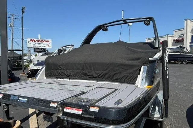 Slide: The Image of 2023 Chaparral 267 SSX boat with cover, displayed at a dealership under clear skies. - 25