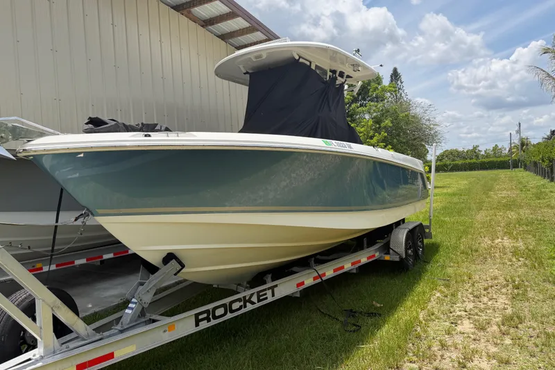 The Image of 2016 Boston Whaler 250 Outrage boat on trailer, parked outdoors under a partly cloudy sky. - 1
