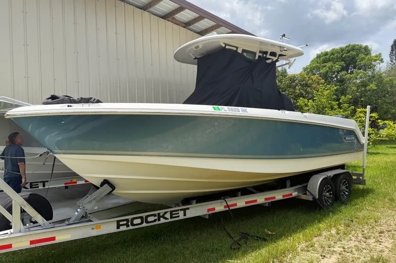 Slide: The Image of 2016 Boston Whaler 250 Outrage on trailer, parked outdoors near a metal building. - 2