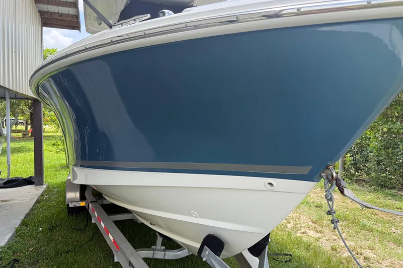 Slide: The Image of 2016 Boston Whaler 250 Outrage boat on trailer, blue hull, parked outdoors. - 4