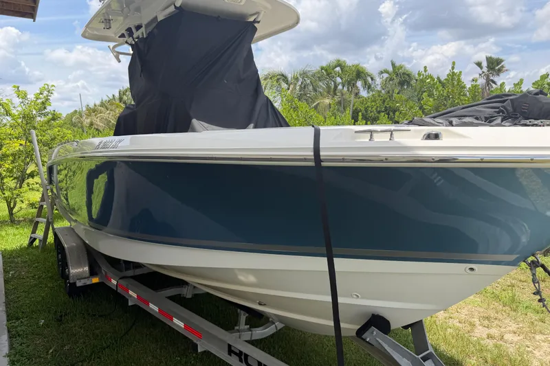 Slide: The Image of 2016 Boston Whaler 250 Outrage boat on trailer, surrounded by lush greenery. - 6