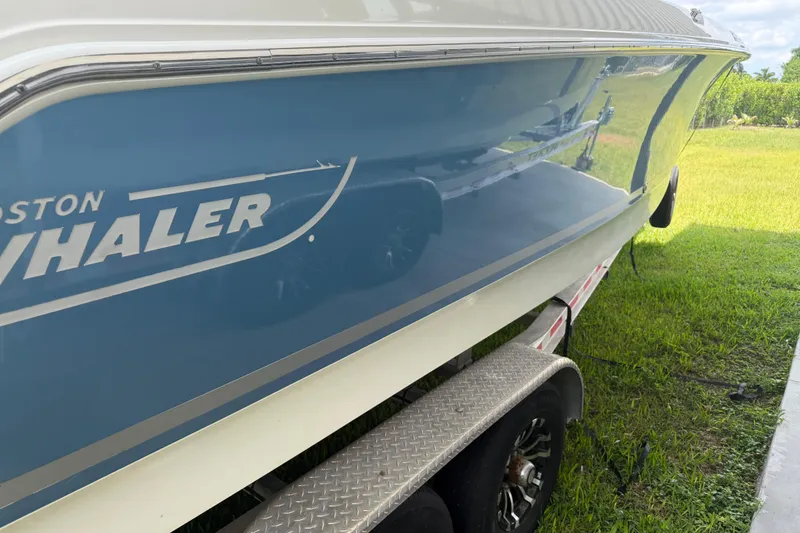 Slide: The Image of 2016 Boston Whaler 250 Outrage boat on trailer, side view with blue hull. - 9