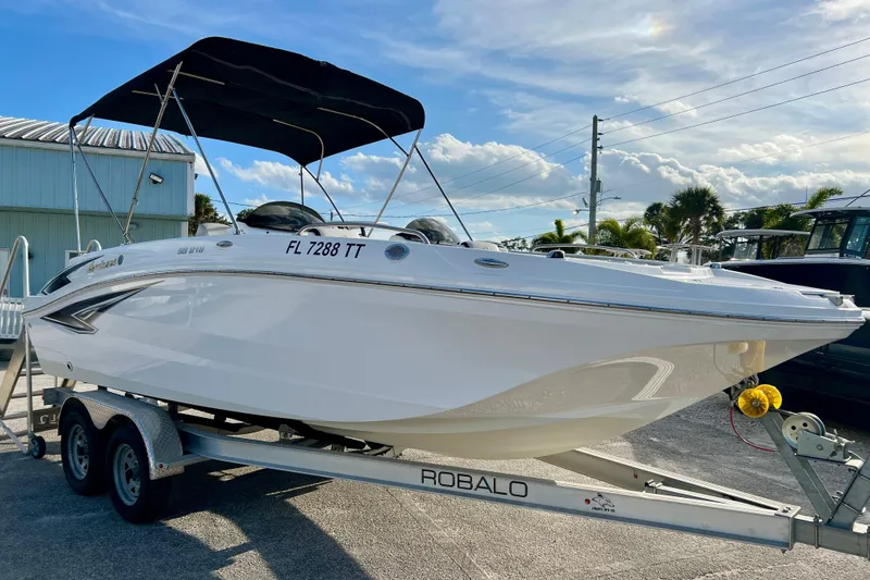 Slide: The Image of 2024 Hurricane Sundeck Sport 218 OB boat on trailer, parked outdoors under blue sky. - 2