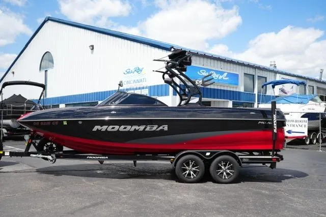 The Image of 2015 Moomba Mojo boat on trailer outside dealership, featuring sleek black and red design. - 1