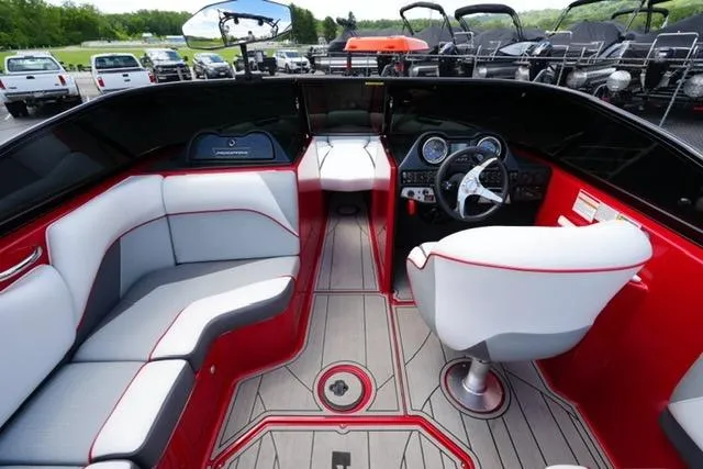 Slide: The Image of 2015 Moomba Mojo boat interior with red and gray seating, modern dashboard, and steering wheel. - 12
