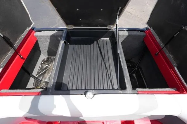 Slide: The Image of Open storage compartment of a 2015 Moomba Mojo boat, featuring red and gray interior. - 18