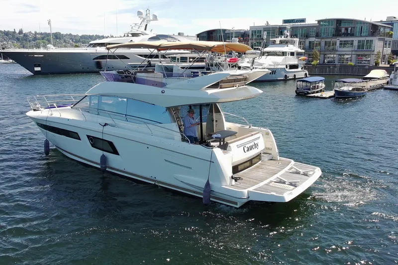 Slide: The Image of 2017 Prestige 500 yacht cruising in a marina with modern buildings in the background. - 2