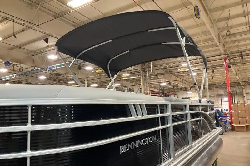 Slide: The Image of 2026 Bennington 23 SX L-Bench pontoon boat with canopy in a warehouse setting. - 5