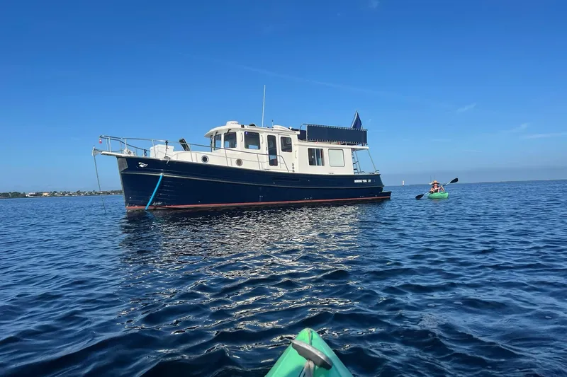 The Image of 2007 Nordic Tug 37 boat on calm blue water with kayaker nearby. - 1