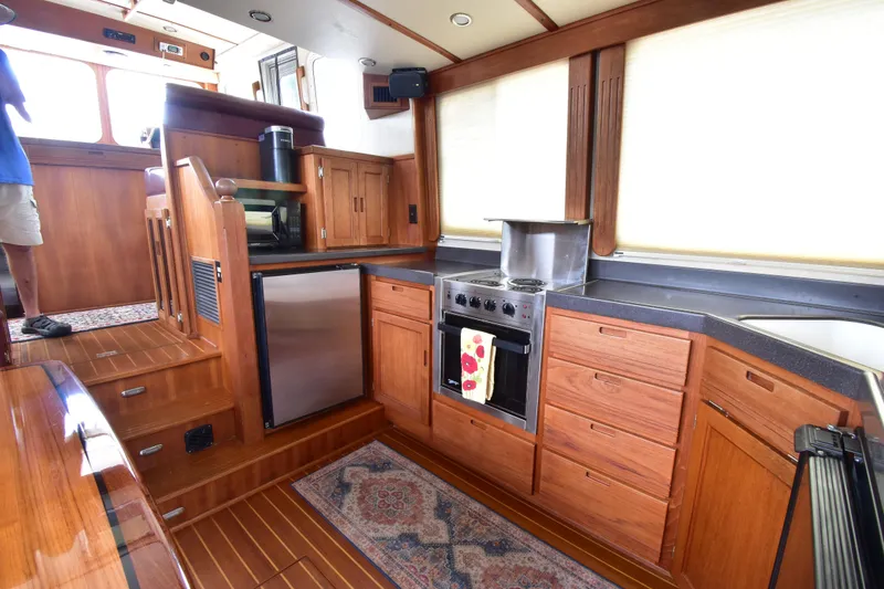 Slide: The Image of Interior of a 2007 Nordic Tug 37, featuring a well-equipped wooden kitchen galley. - 14
