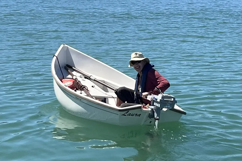 Slide: The Image of A person in a small boat named "Laura" on clear blue water, smiling and wearing a hat. - 27