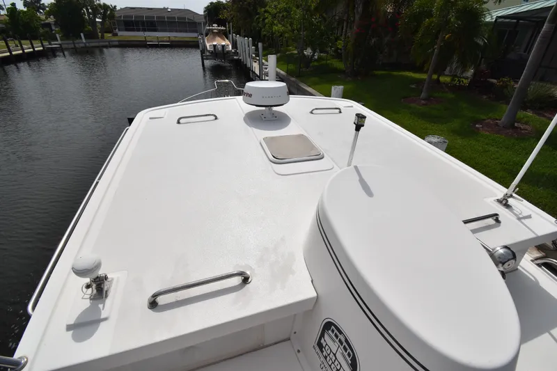 Slide: The Image of 2007 Nordic Tug 37 boat deck with radar and hatch, docked by lush greenery. - 7