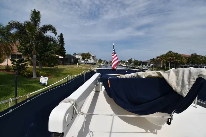 Slide: The Image of 2007 Nordic Tug 37 docked, featuring American flag and lush waterfront scenery. - 8