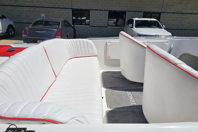 Slide: The Image of 1997 Donzi 18 Classic boat interior with white and red-trimmed seating, parked near vehicles. - 10