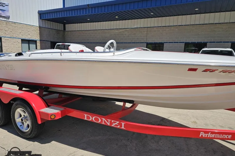 Slide: The Image of 1997 Donzi 18 Classic boat on red trailer, parked outside a building. - 13