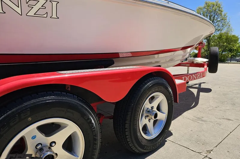Slide: The Image of 1997 Donzi 18 Classic boat on a red trailer, showcasing sleek design and wheels. - 19