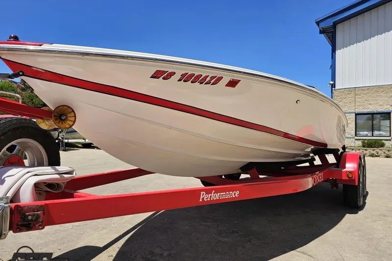 Slide: The Image of 1997 Donzi 18 Classic boat on red trailer, parked outdoors under clear blue sky. - 27